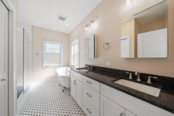 a spacious bathroom with a granite countertop sink a toilet a mirror and a shower