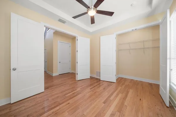 an empty room with wooden floor a ceiling fan and closet
