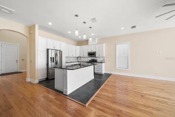a large kitchen with a refrigerator and wooden floor