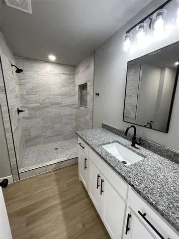a bathroom with a granite countertop sink mirror and a bathtub