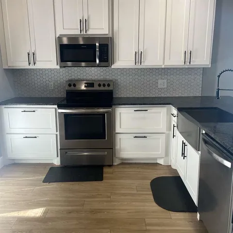 a kitchen with granite countertop a stove and a microwave