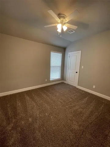 an empty room with a chandelier fan and windows