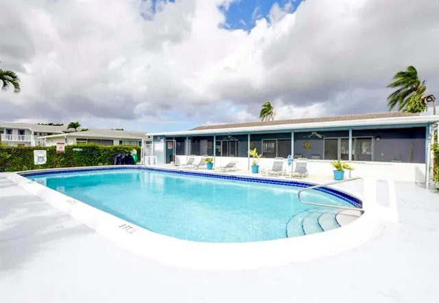 a view of house with swimming pool and view of tall trees