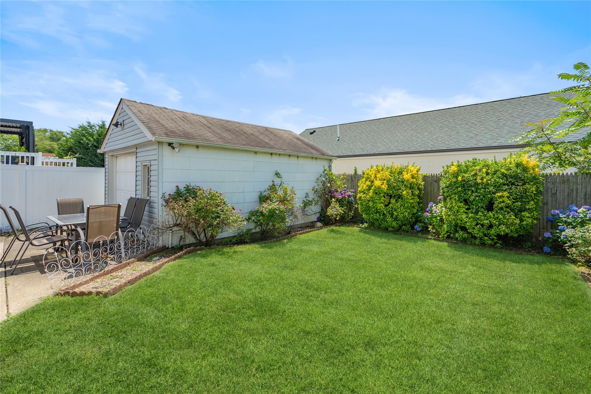 12 Westmoreland Road Merrick, NY 11566 - Photo 5 of 42 a backyard of a house with table and chairs plants and large tree