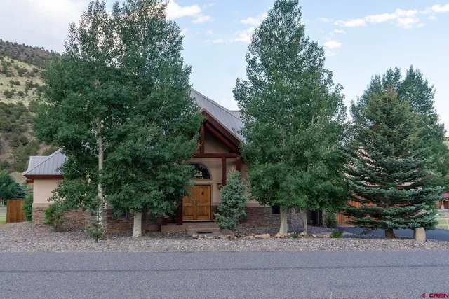 a view of a house with a yard plants and large tree