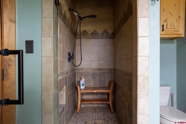 a view of a hallway with wooden floor and a bathroom