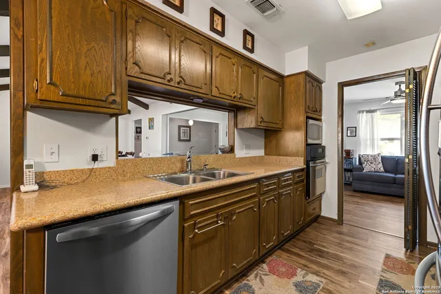 a kitchen with stainless steel appliances granite countertop a sink a stove and cabinets