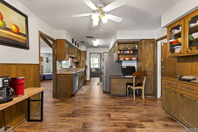 a kitchen with stainless steel appliances kitchen island granite countertop a refrigerator a stove and a dining table with wooden floor