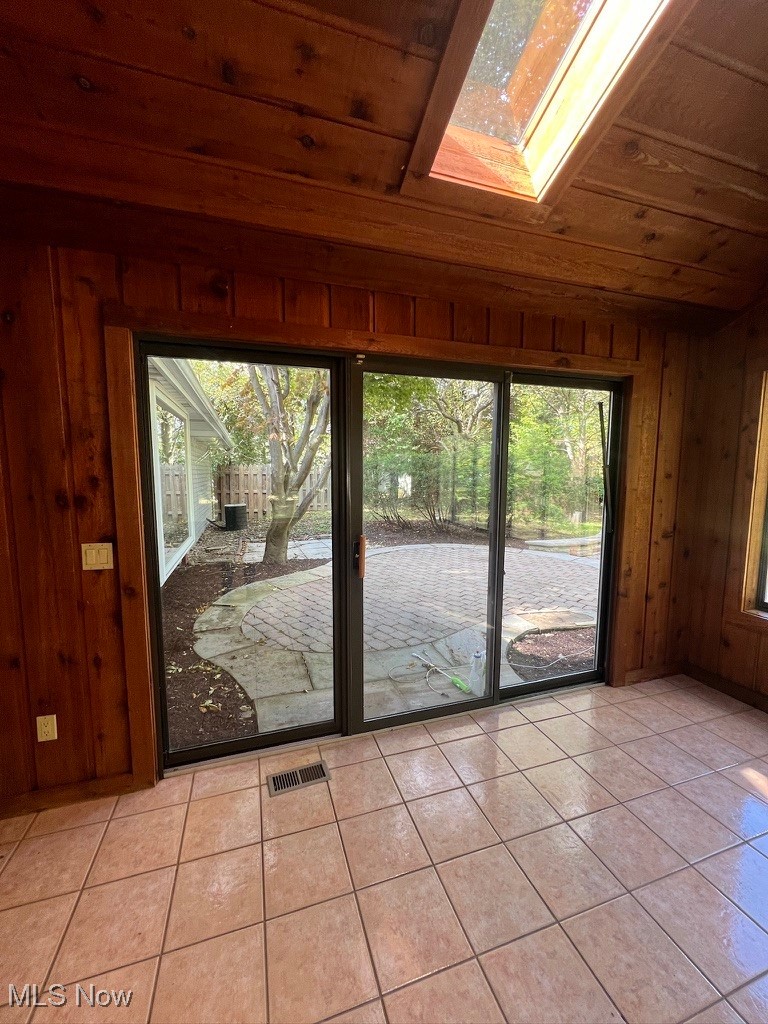 11331 Palmer Road Painesville, OH 44077 - Photo 35 of 47 Doorway to outside featuring a skylight, wooden walls, wood ceiling, and light tile patterned floors