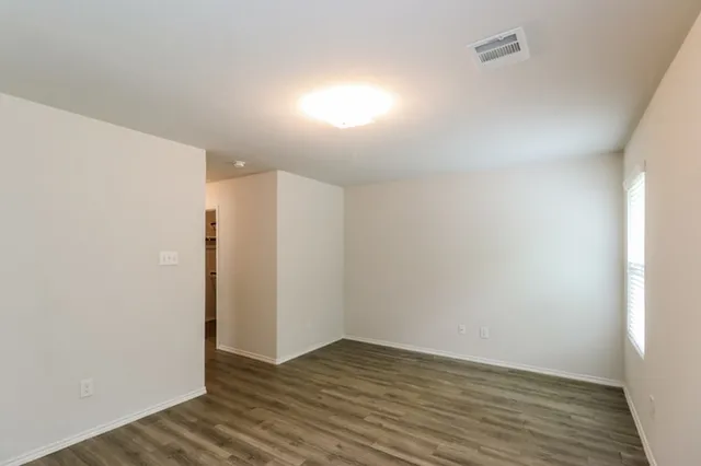 a view of an empty room with wooden floor and a window