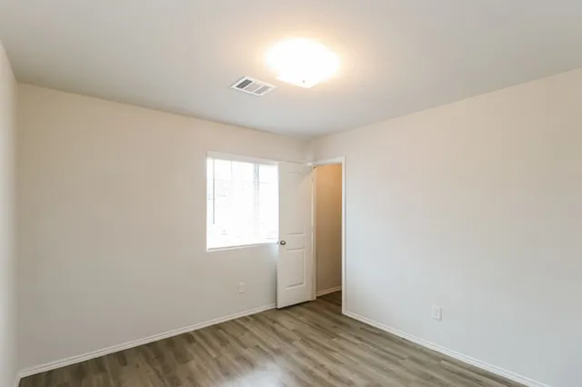 an empty room with wooden floor and windows