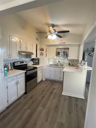 a kitchen with stainless steel appliances a sink a stove a refrigerator cabinets and a window