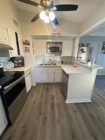 a large kitchen with cabinets a sink and stainless steel appliances
