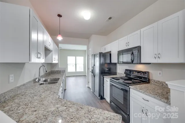 a kitchen with granite countertop a sink stainless steel appliances and cabinets