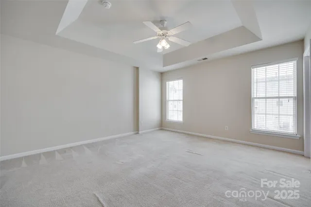 an empty room with windows and chandelier fan
