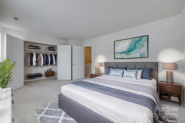 a spacious bedroom with a bed a wall painting and a potted plant