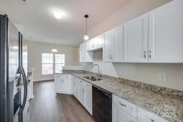 a kitchen with granite countertop a sink a counter space appliances and cabinets