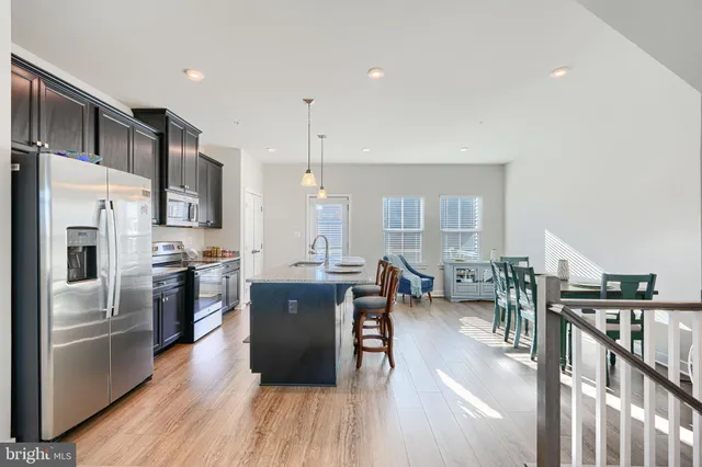 a kitchen with stainless steel appliances granite countertop a refrigerator a oven a stove and a wooden floors