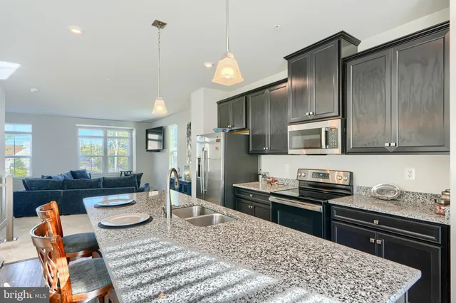 a kitchen with stainless steel appliances granite countertop a refrigerator a stove a sink dishwasher a dining table and chairs with wooden floor