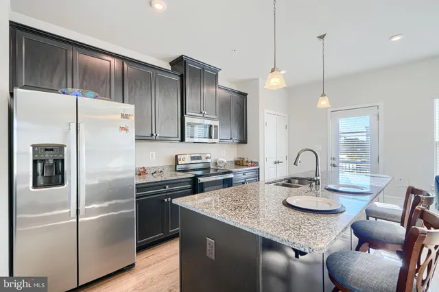 a kitchen with stainless steel appliances granite countertop a sink refrigerator and cabinets
