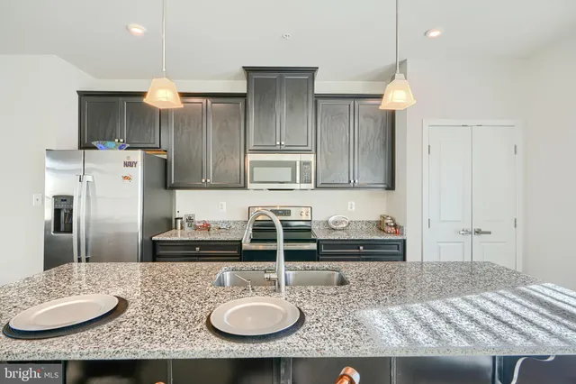 a kitchen with kitchen island granite countertop a sink refrigerator and cabinets