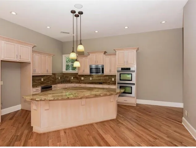 a large kitchen with stainless steel appliances granite countertop a stove a sink and a wooden floors