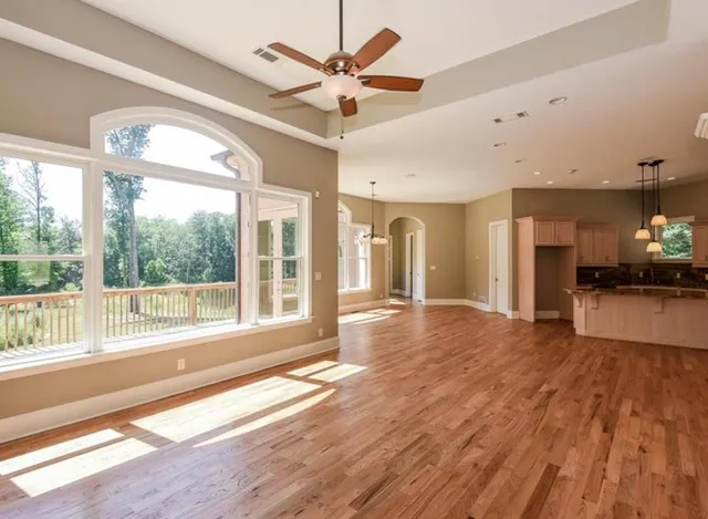 a view of an empty room with a window and wooden floor