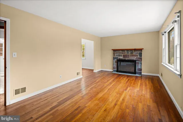 an empty room with wooden floor cabinet and windows