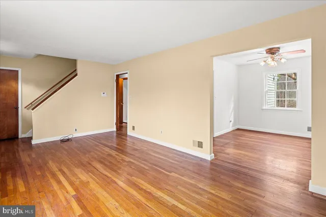 a view of an empty room with a window and wooden floor