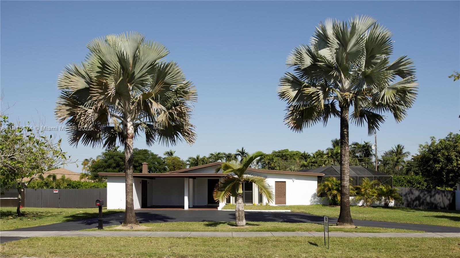 front view of house with a yard and palm trees