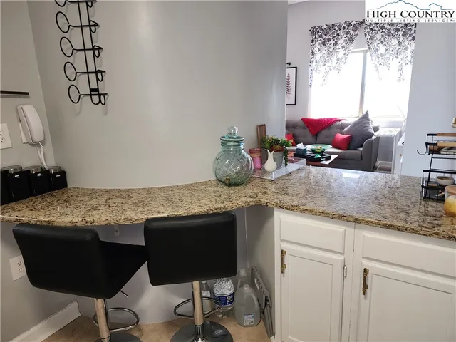 a kitchen with a granite countertop sink a window and chairs
