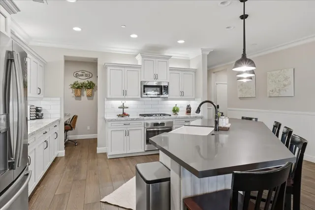 a kitchen with granite countertop stainless steel appliances white cabinets and a stove