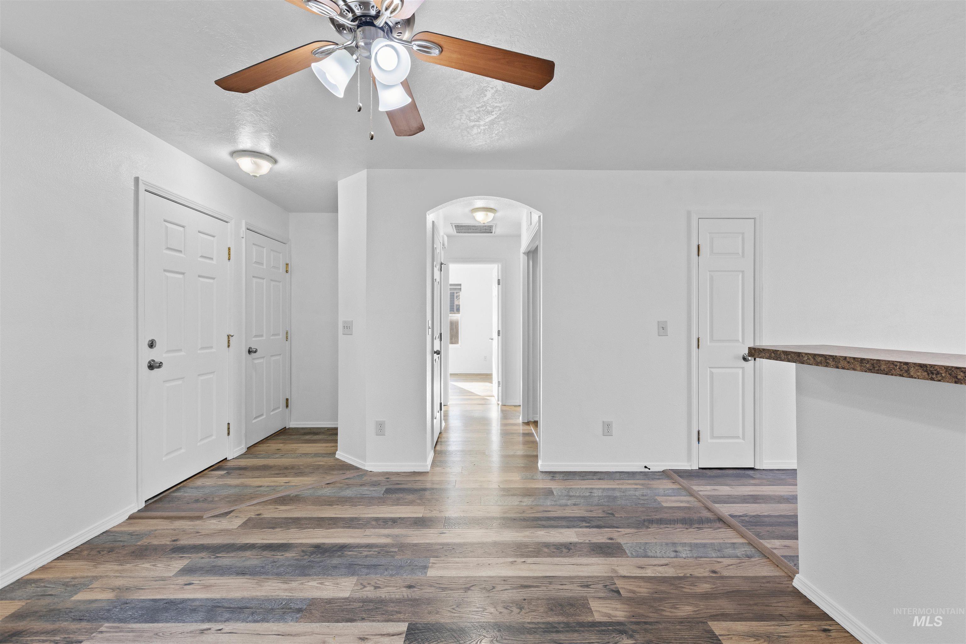 16535 Chino Avenue Caldwell, ID 83607 - Photo 5 of 26 Unfurnished room featuring dark wood-style flooring, arched walkways, and ceiling fan