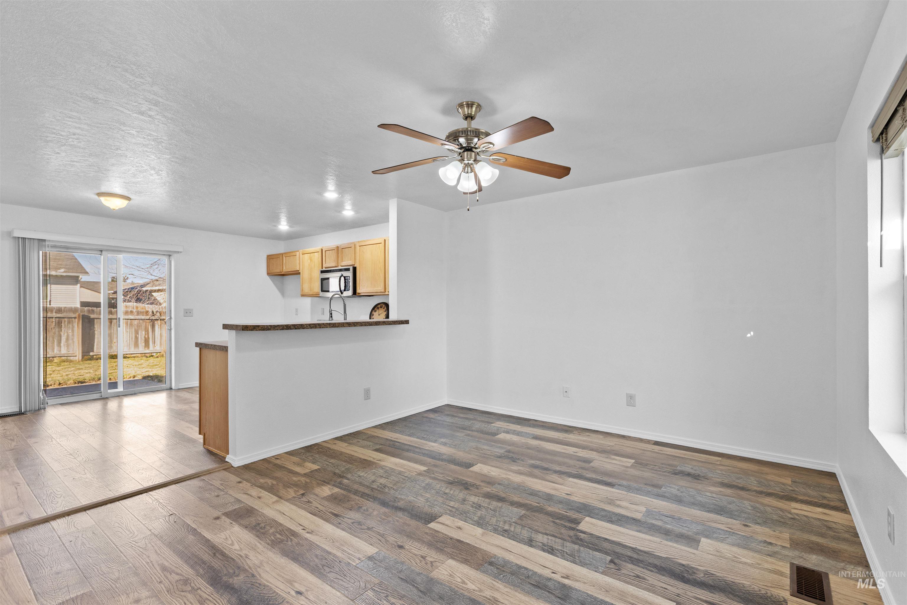 16535 Chino Avenue Caldwell, ID 83607 - Photo 7 of 26 Unfurnished living room with ceiling fan, dark wood finished floors, and a textured ceiling