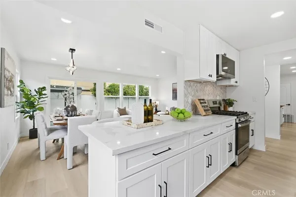 a kitchen with stainless steel appliances kitchen island granite countertop a sink a stove and a wooden floors