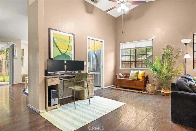 a living room with furniture a flat screen tv and a refrigerator