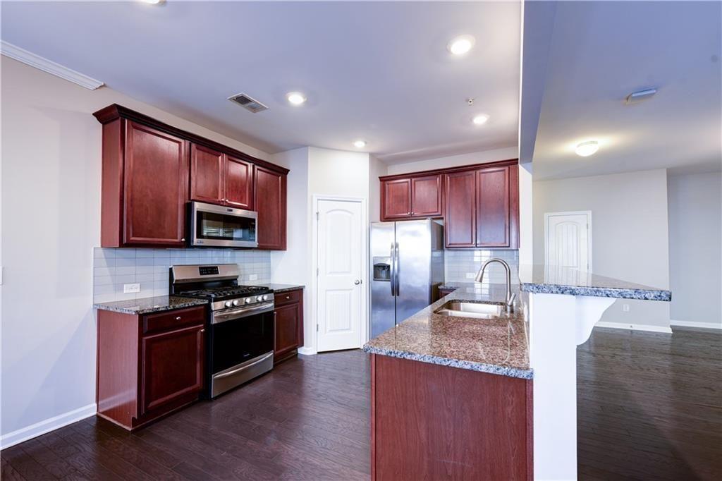 1226 Fischer Trace Cumming, GA 30041 - Photo 3 of 24 a kitchen with stainless steel appliances granite countertop a stove top oven a sink dishwasher a refrigerator and a microwave