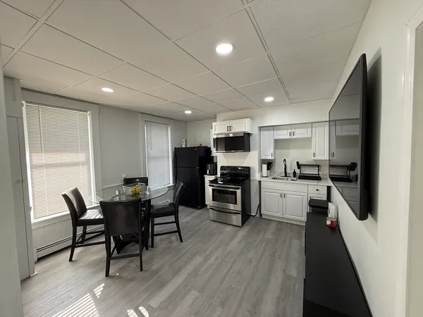 a kitchen with stainless steel appliances kitchen island granite countertop a table chairs microwave and sink