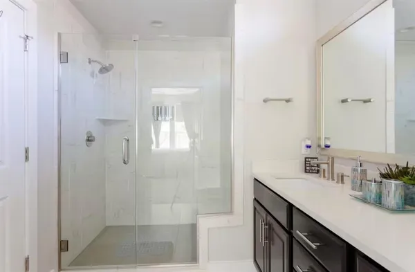 a bathroom with a shower sink vanity and mirror