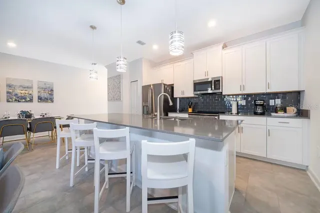 a kitchen with stainless steel appliances granite countertop a stove top oven a sink a dining table and chairs