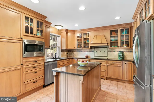 a kitchen with stainless steel appliances granite countertop a stove top oven a dining table and chairs