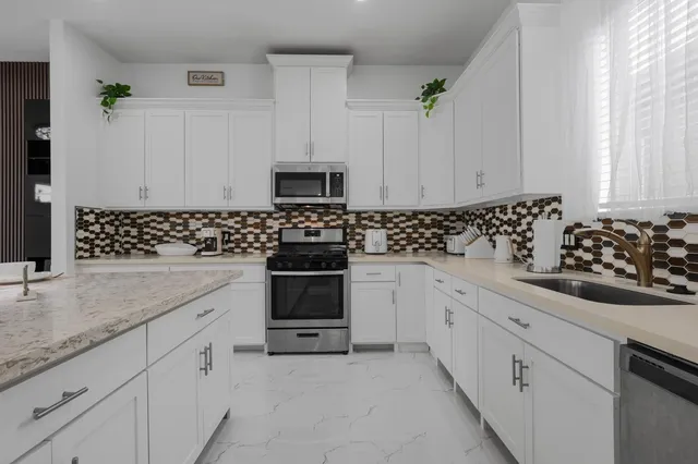 a kitchen with stainless steel appliances granite countertop a table chairs sink and cabinets