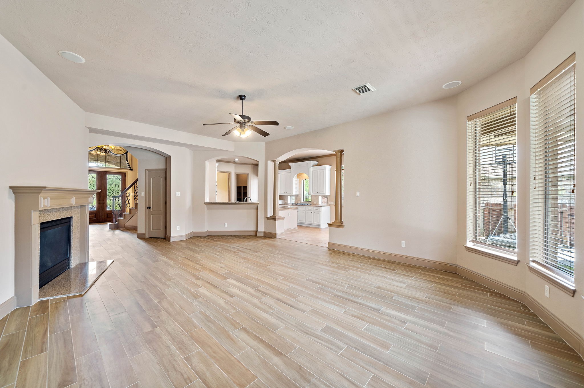 10015 Cinco Ridge Drive Katy, TX 77494 - Photo 6 of 17 an empty room with wooden floor fireplace and windows