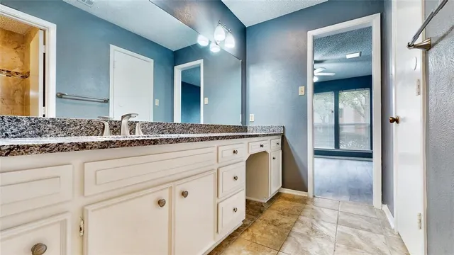 a spacious bathroom with a granite countertop sink and a mirror