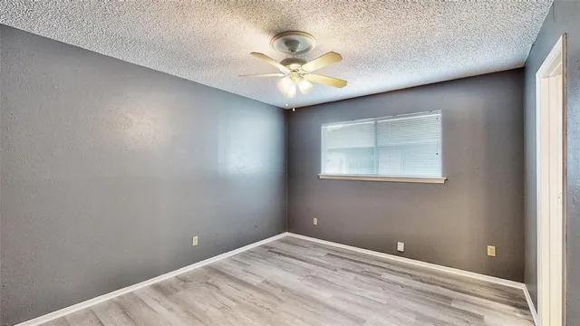 an empty room with a ceiling fan and wooden floor