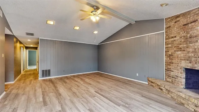 a view of empty room with a fireplace and wooden floor