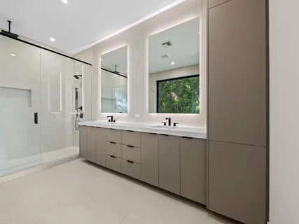 a bathroom with a double vanity sink a large mirror and a bathtub