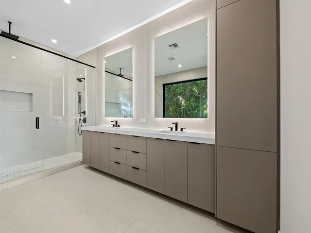 a bathroom with a double vanity sink a large mirror and a bathtub