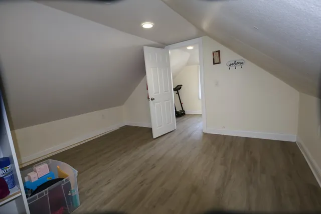 a view of an empty room with wooden floor and stairs