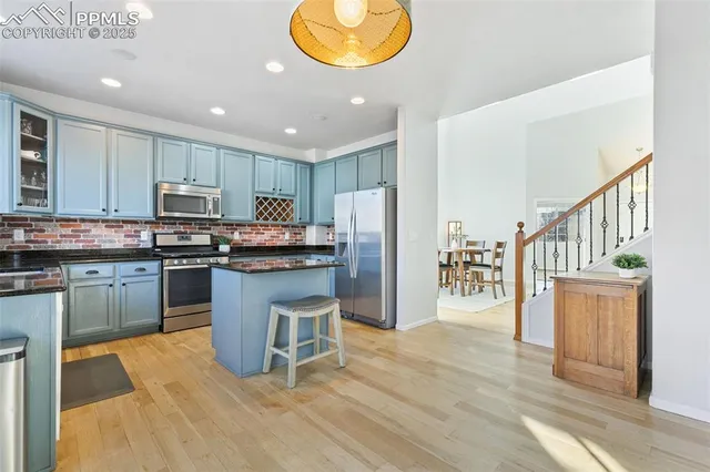 a kitchen with kitchen island granite countertop wooden floors stainless steel appliances and sink